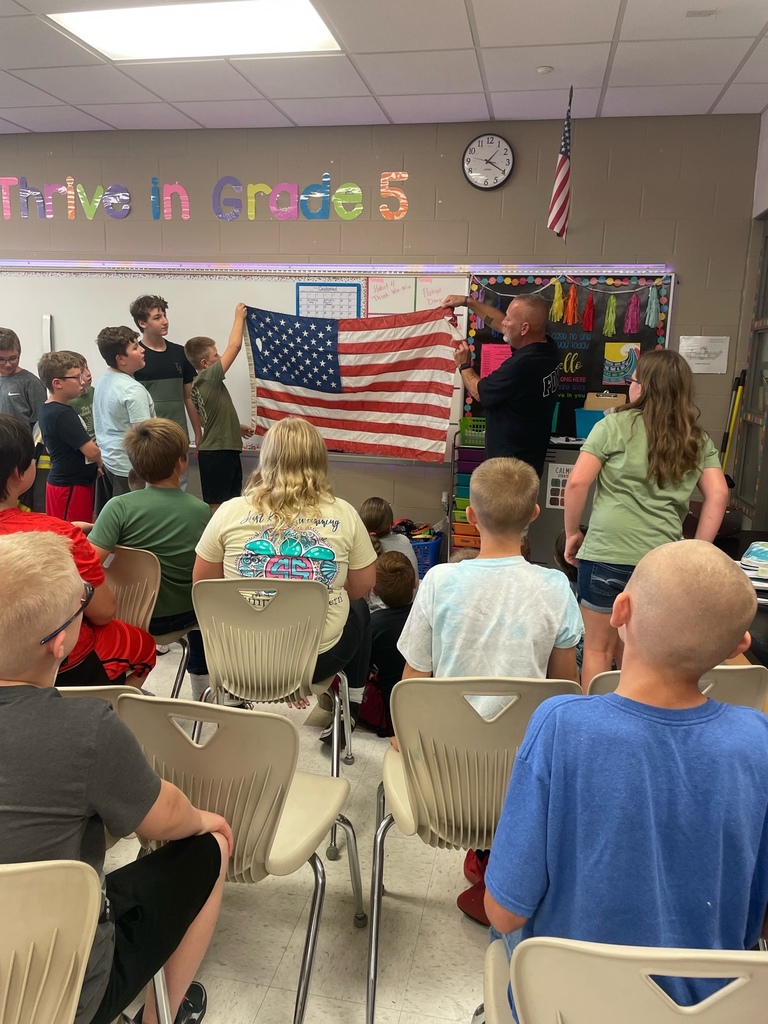 students in classroom holding USA flag